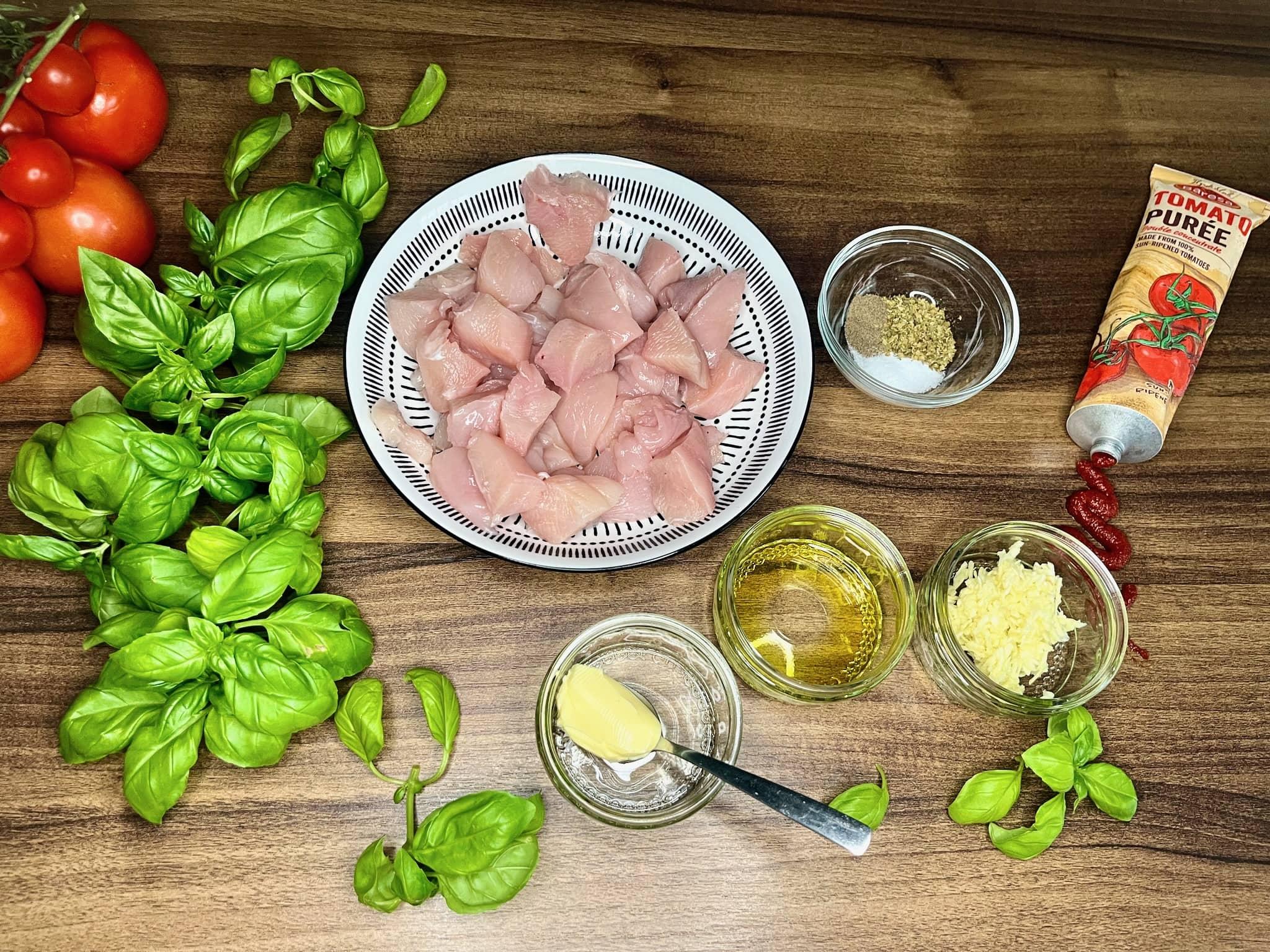 ingredients for tomato basil chicken casserole laid out on a wooden table