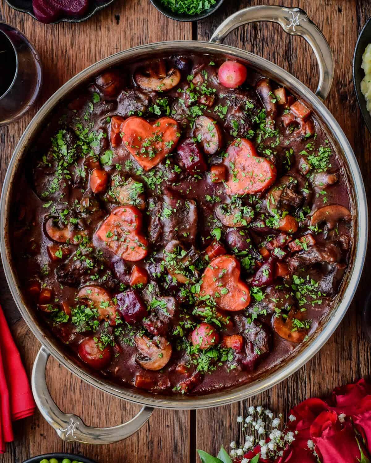 Close-up of browned beef chunks and vibrant aromatic vegetables (onions, garlic, ginger) sautéing in a Dutch oven.