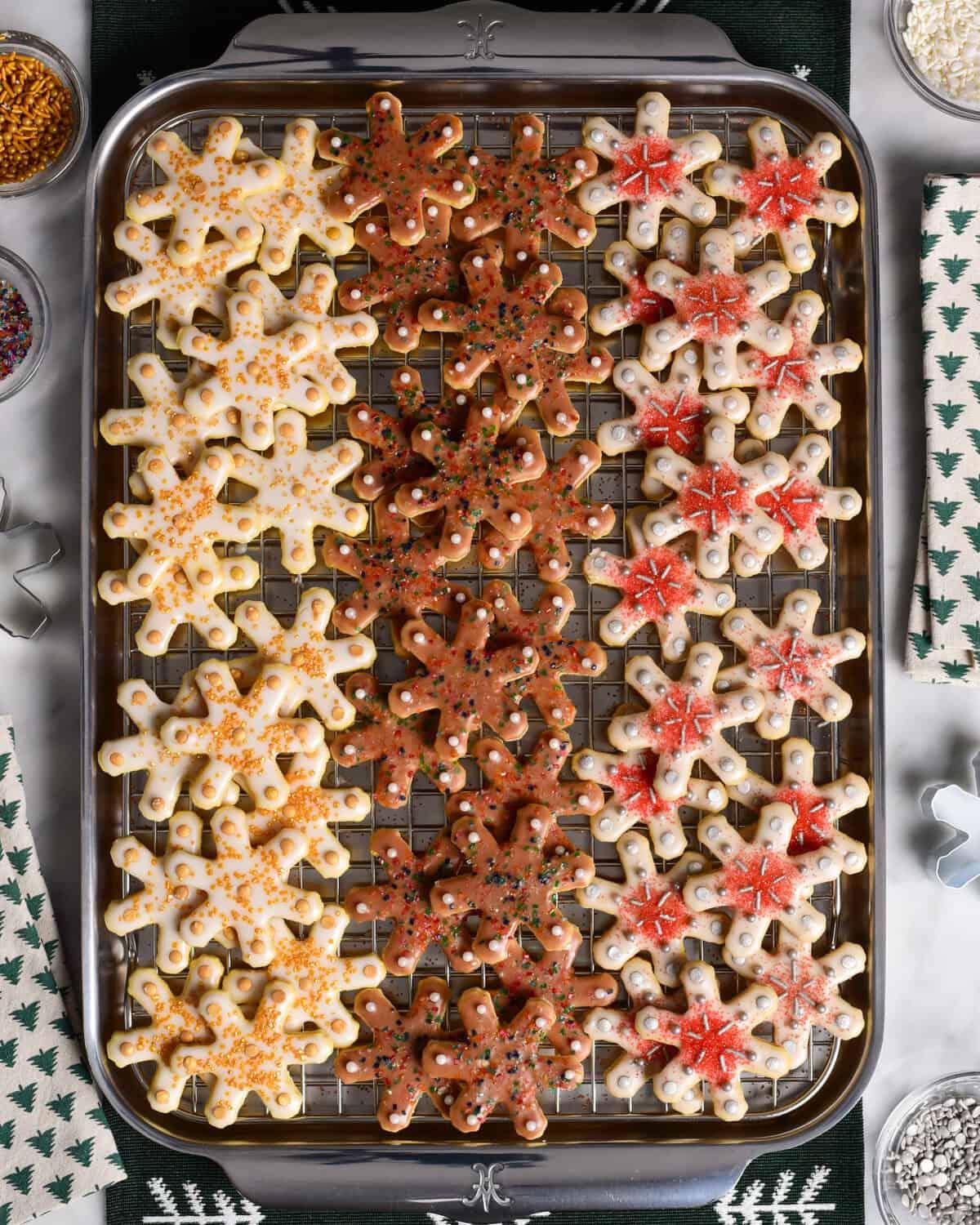 beautifully decorated glistening snowflake sugar cookies on a rustic wooden holiday platter with fairy lights