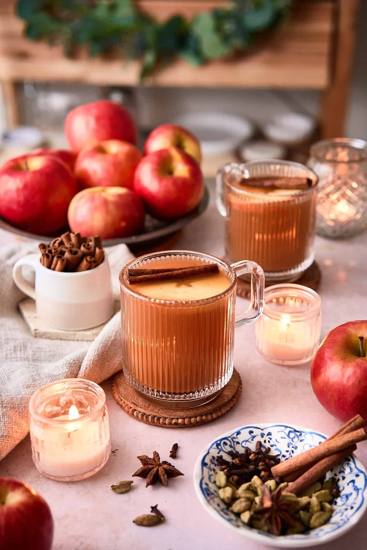 steaming mug of spiced apple cider with cinnamon sticks and orange slices, cozy Friendsgiving setting