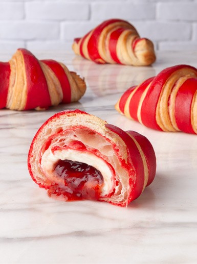 Close-up shot of red velvet croissants with cream cheese frosting, arranged on a wire rack