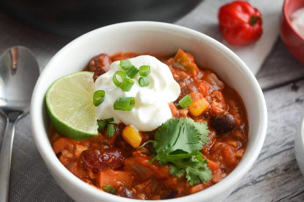 A hearty bowl of vegetarian chili, garnished with fresh cilantro and a dollop of sour cream.
