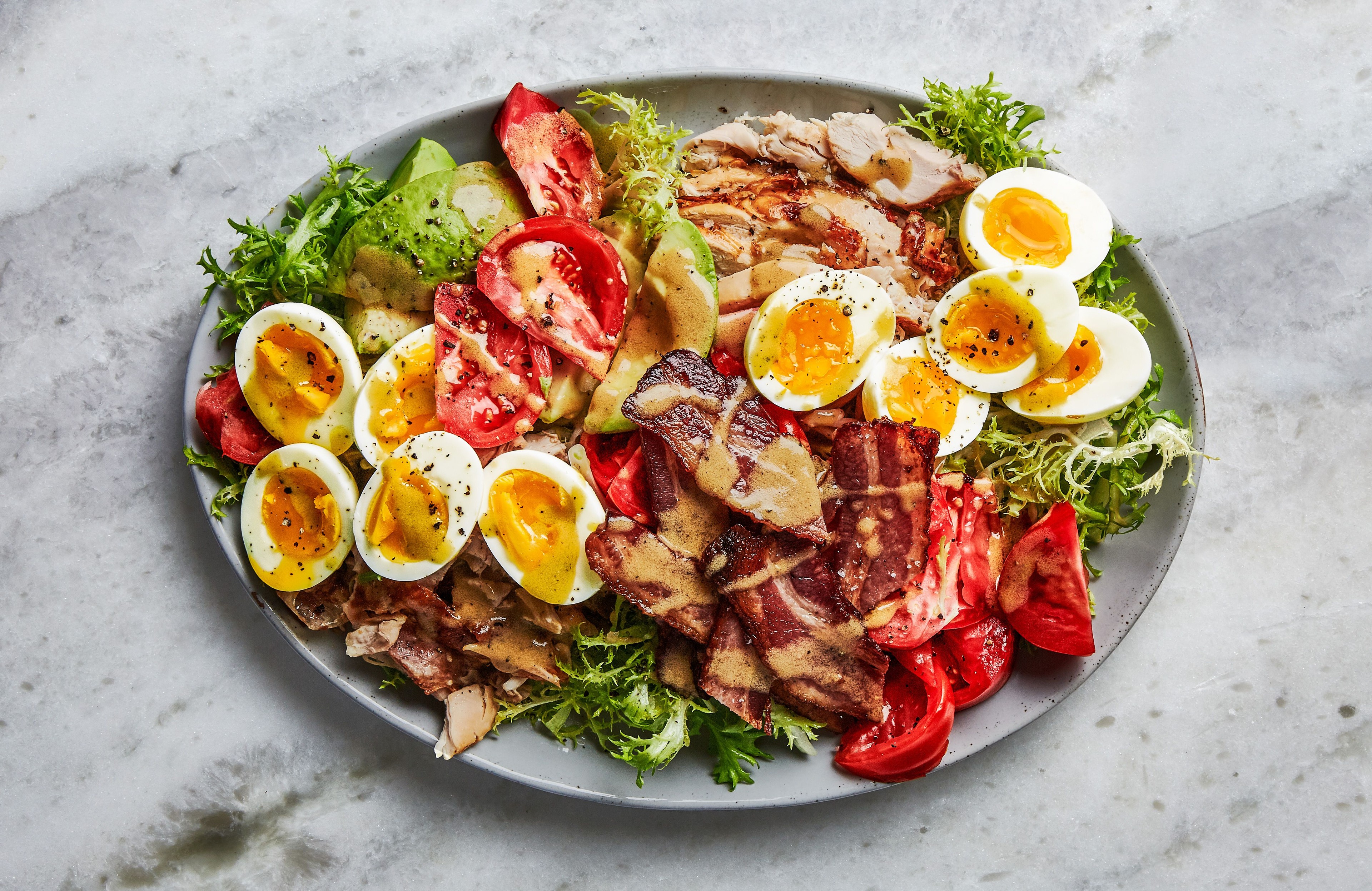 Hard-boiled egg and bacon Cobb salad on a rustic wooden table