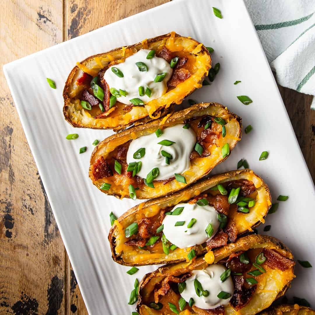 Crispy potato skins loaded with bacon and cheese, garnished with green onions