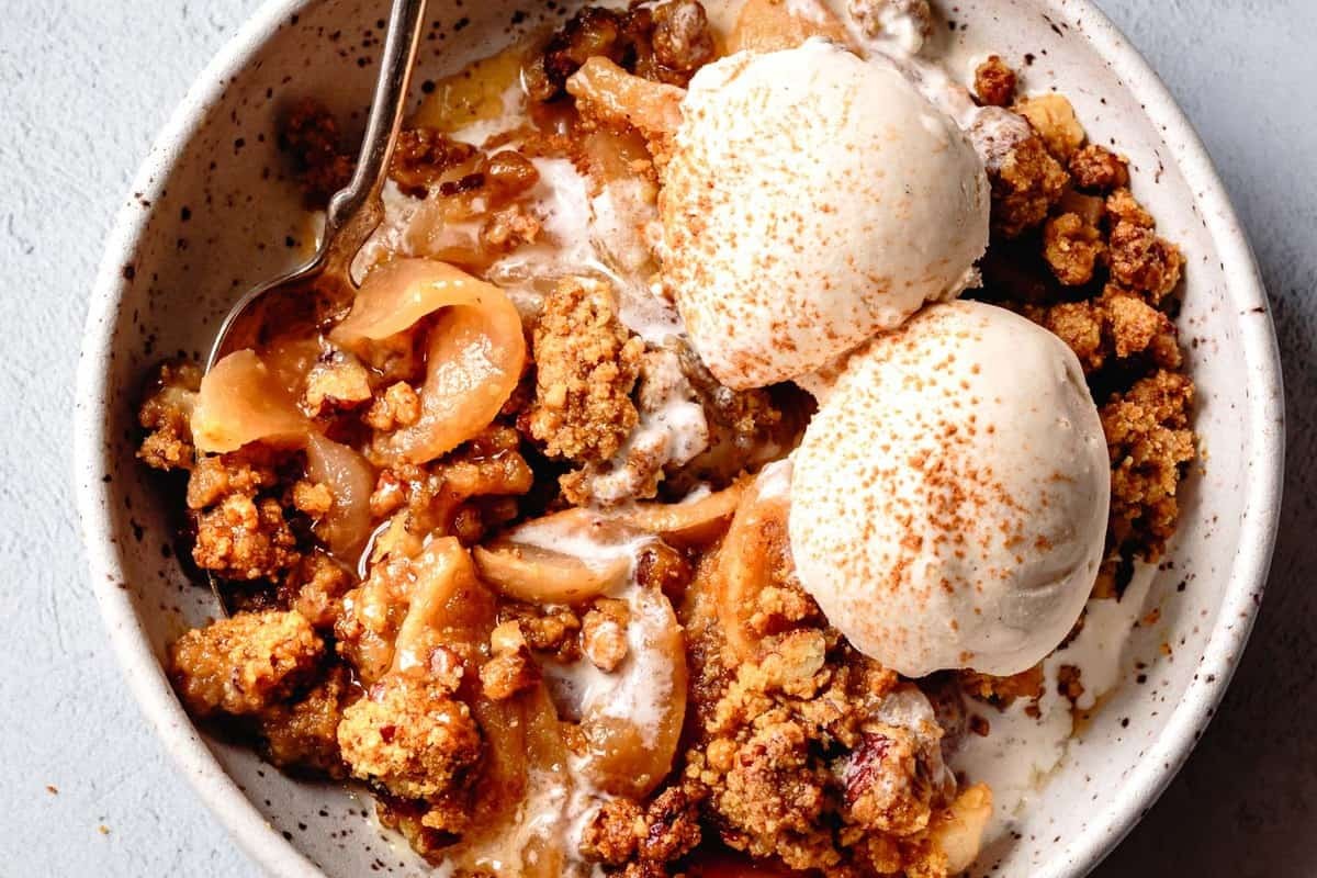 A rustic, golden-brown paleo fruit cobbler with a slightly crunchy almond flour topping, served warm with a scoop of vanilla coconut cream or ice cream