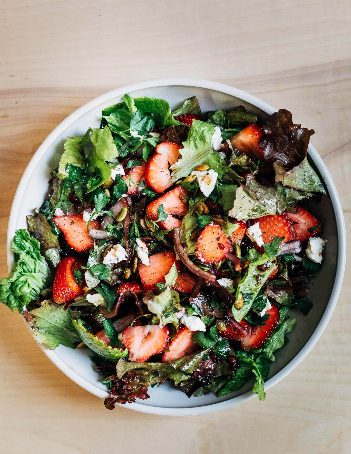 A vibrant Strawberry Green Goddess Salad in a rustic bowl, garnished with fresh herbs and strawberries