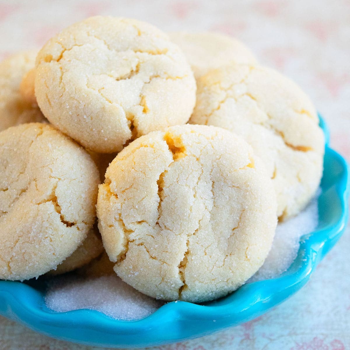 Pile of golden soft chewy sugar cookies with slight cracks, white background, warm lighting