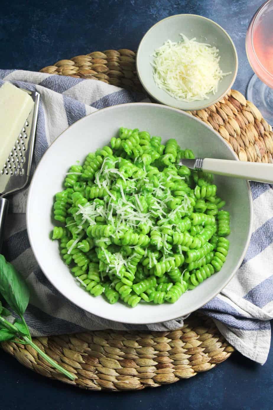 A close-up shot of a plate of pasta with a vibrant green spinach pesto sauce