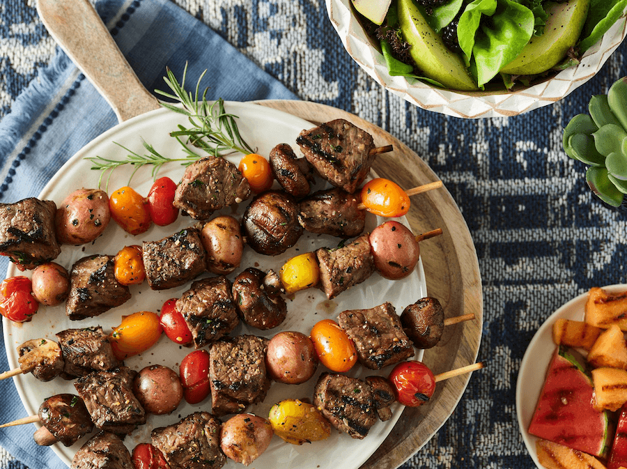 Delicious beef kebabs sizzling on a grill with garlic herb butter