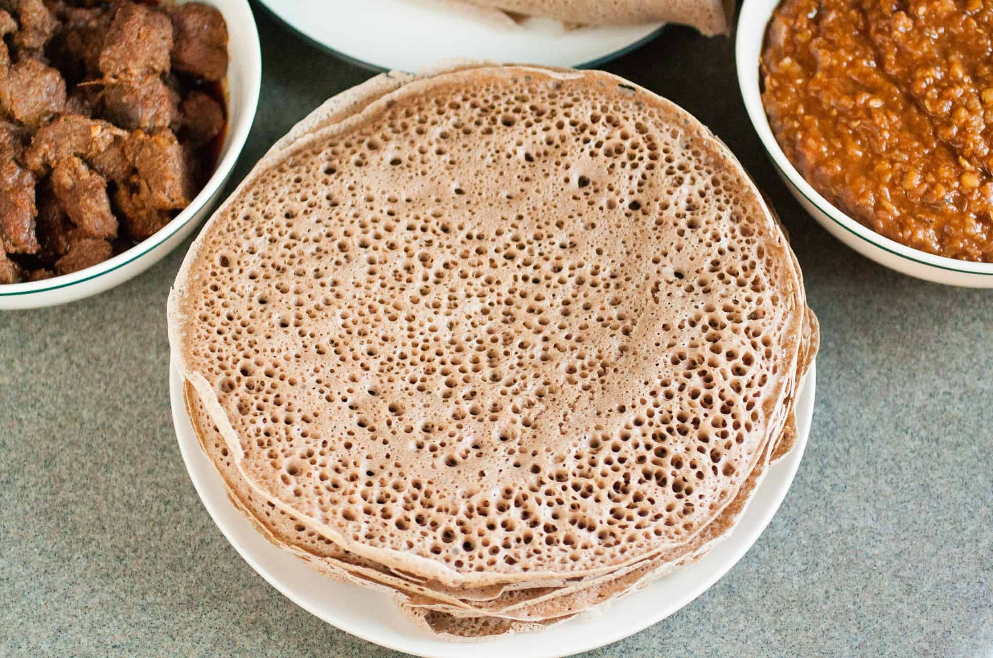 Injera breadcrumbs being sprinkled on a colorful plate of Ethiopian food