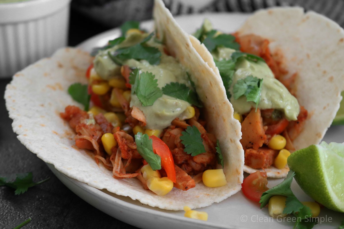 Close-up shot of delicious jackfruit tacos with a vibrant lime-cilantro salsa, garnished with fresh cilantro and lime wedges.