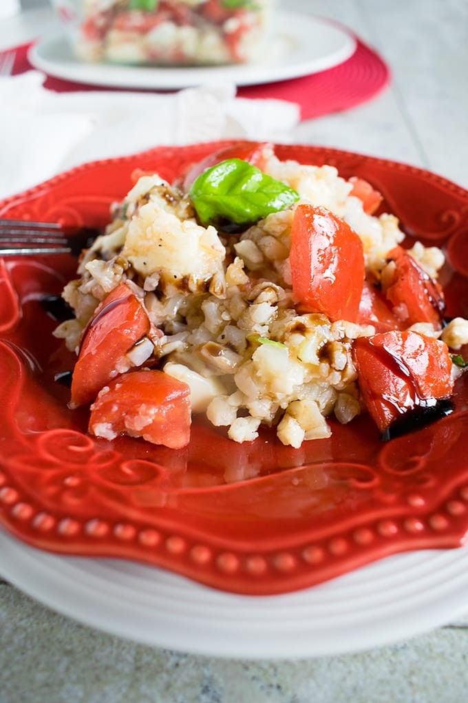 A vibrant close-up shot of cauliflower rice topped with a glistening balsamic glaze, garnished with fresh herbs.