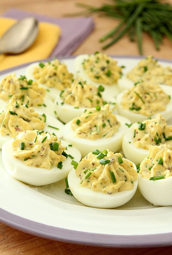 Close-up of elegant deviled eggs garnished with gin and tonic, herbs and citrus zest