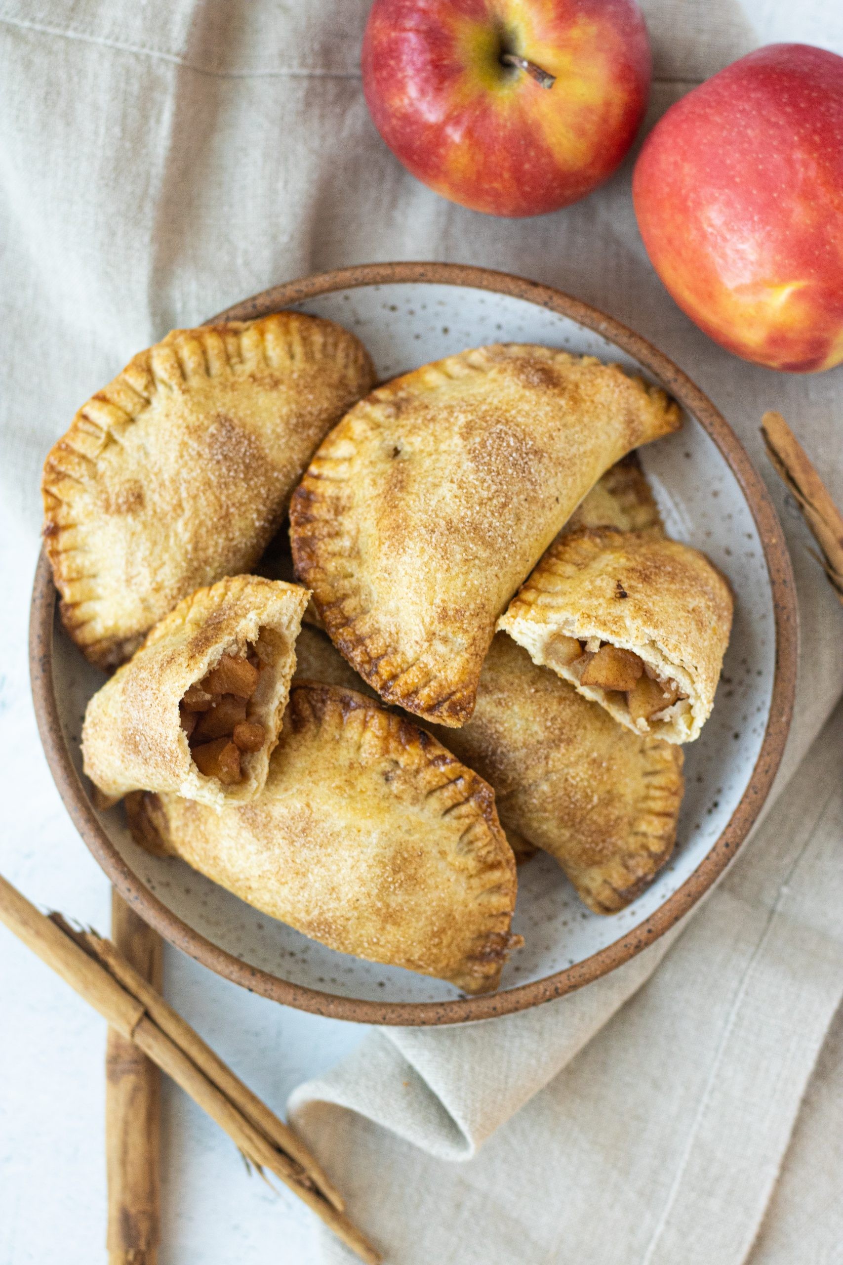 golden-brown apple empanadas with cinnamon dusting, rustic setting