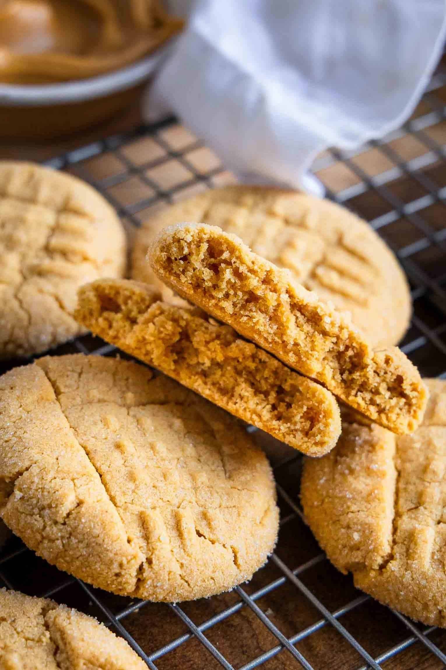 Close-up of freshly baked peanut butter cookies with visible fork marks, crackly edges, and a warm, soft center, on a cooling rack.