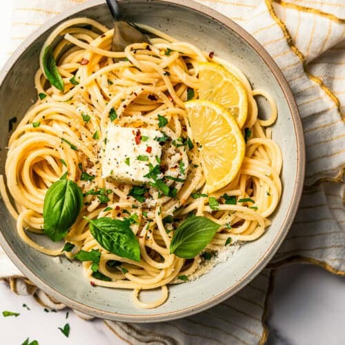 A vibrant bowl of garlic herb pasta, garnished with fresh parsley and parmesan, ready to eat, cozy kitchen background with warm lighting