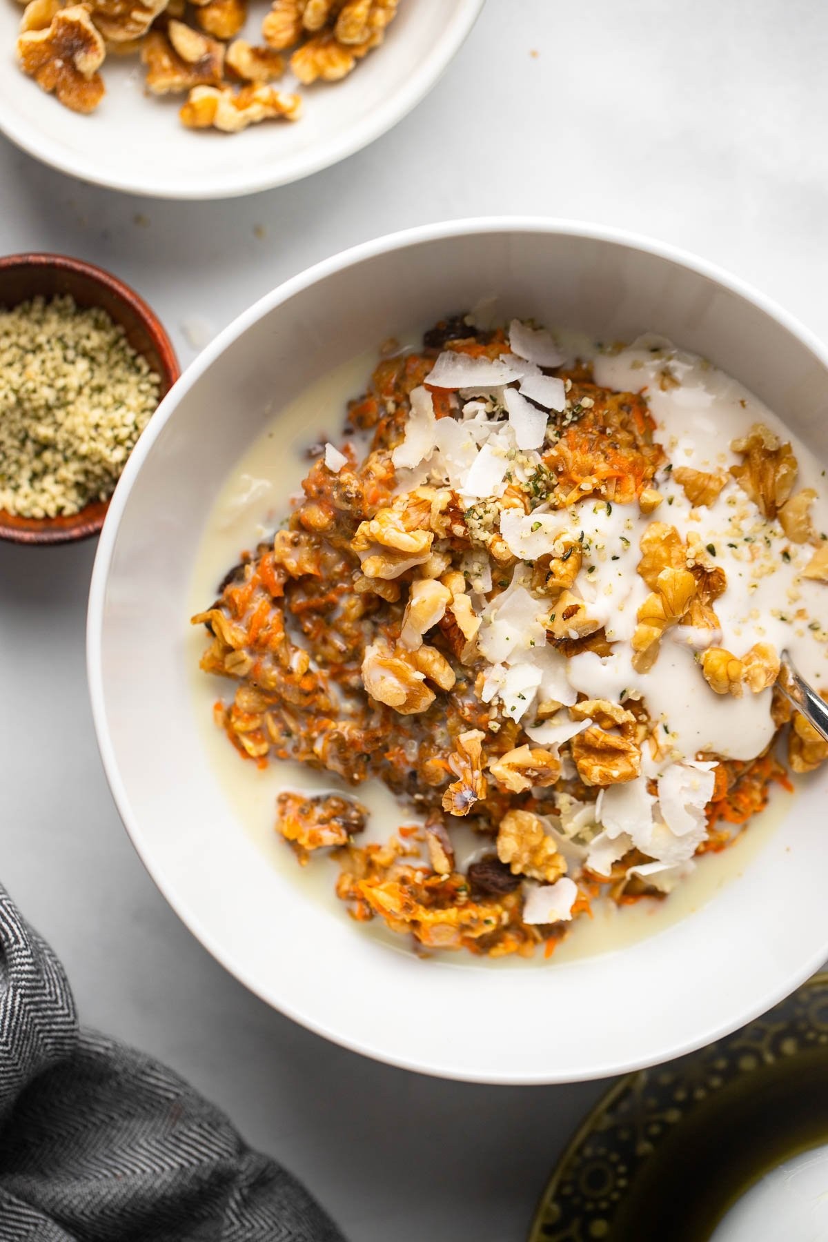 a bowl of carrot cake oatmeal topped with walnuts and coconut flakes