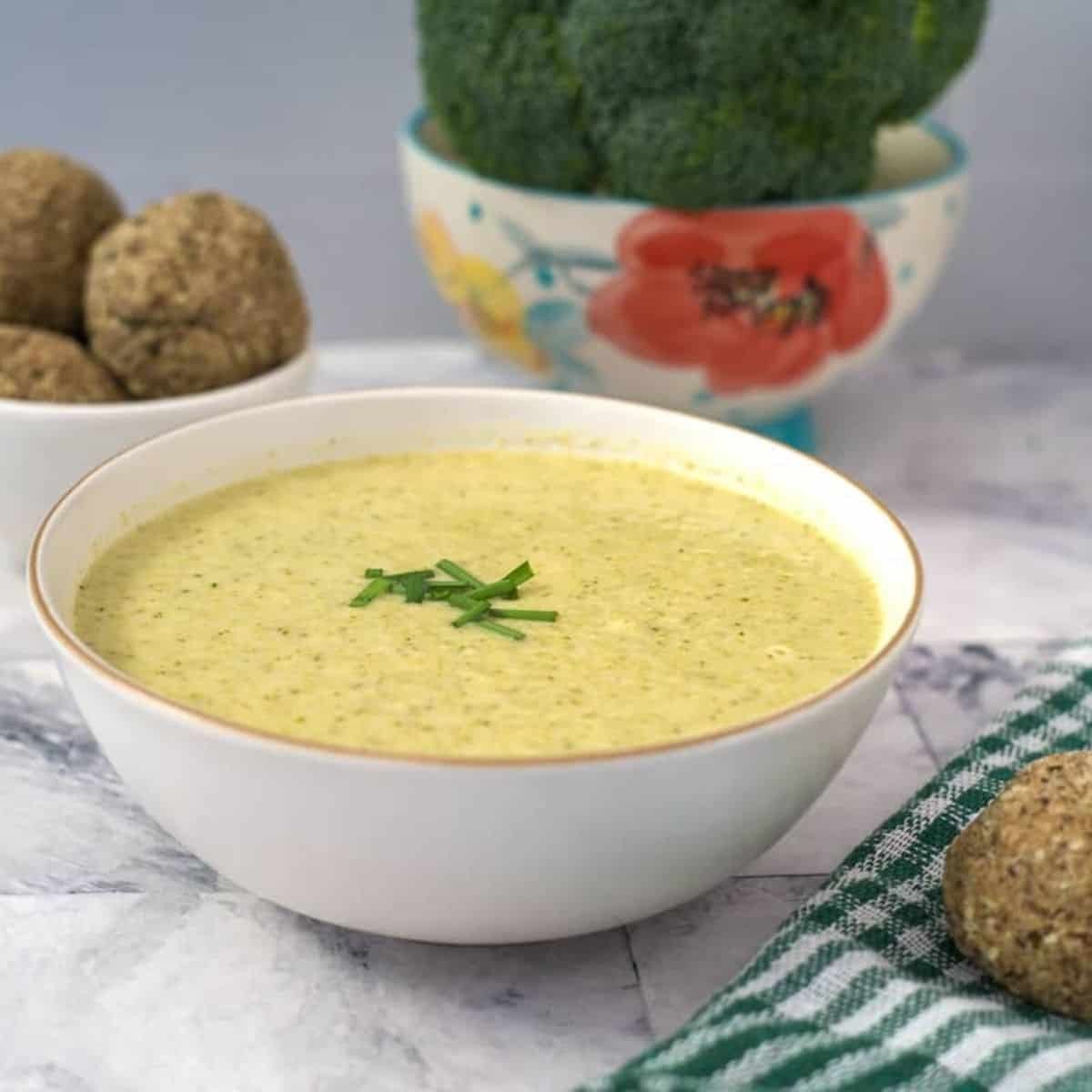 bowl of broccoli and ginger soup topped with coconut cream and sesame seeds