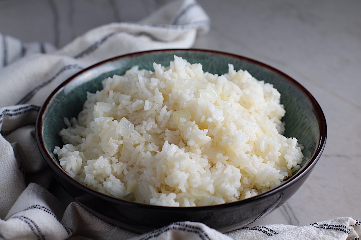 A bowl of fluffy boiled rice topped with sauteed onions