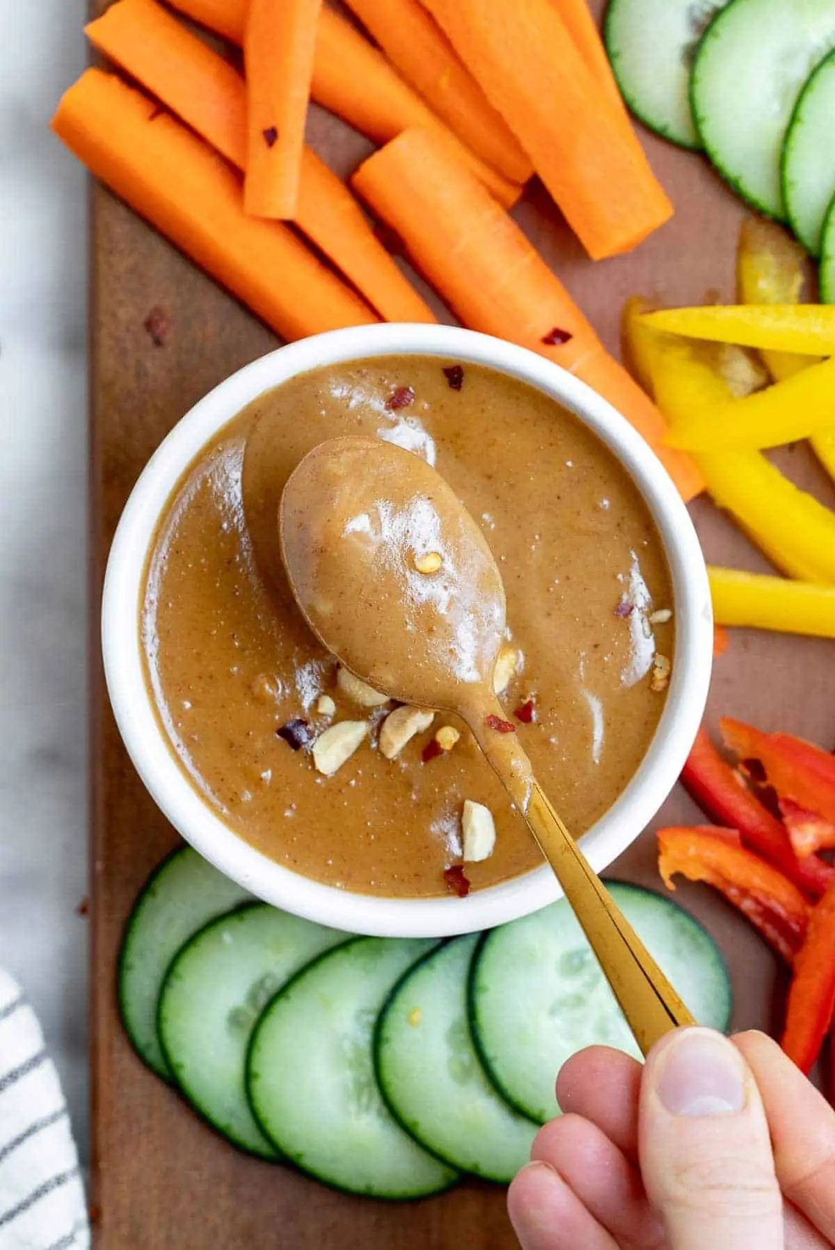 spicy peanut dip with rice crackers on a wooden board