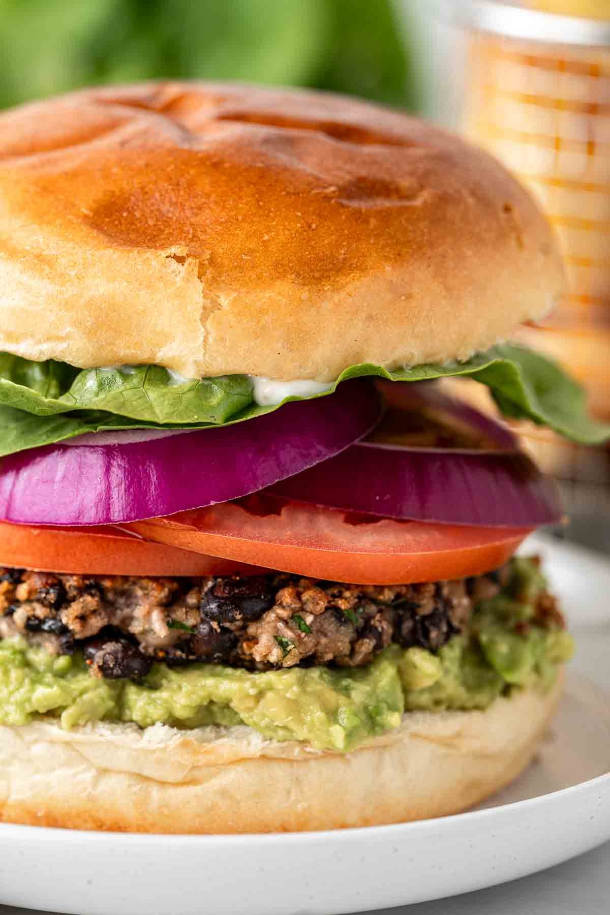 Close-up shot of juicy basil and black bean burgers on brioche buns with fresh basil garnish