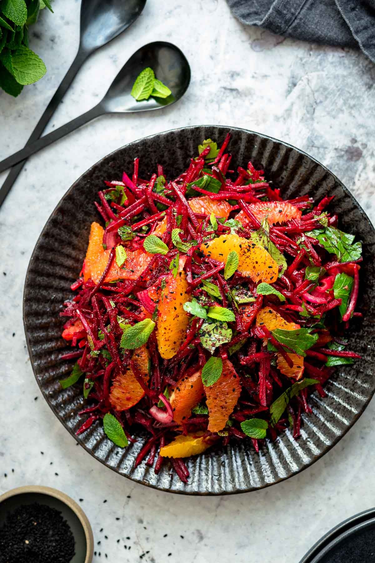 Close-up shot of a vibrant chilled beetroot and orange salad, garnished with fresh herbs