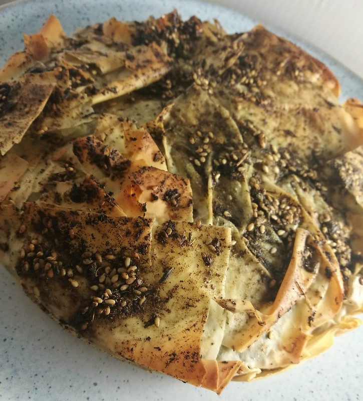 golden brown spanakopita with za'atar bread on a rustic wooden table