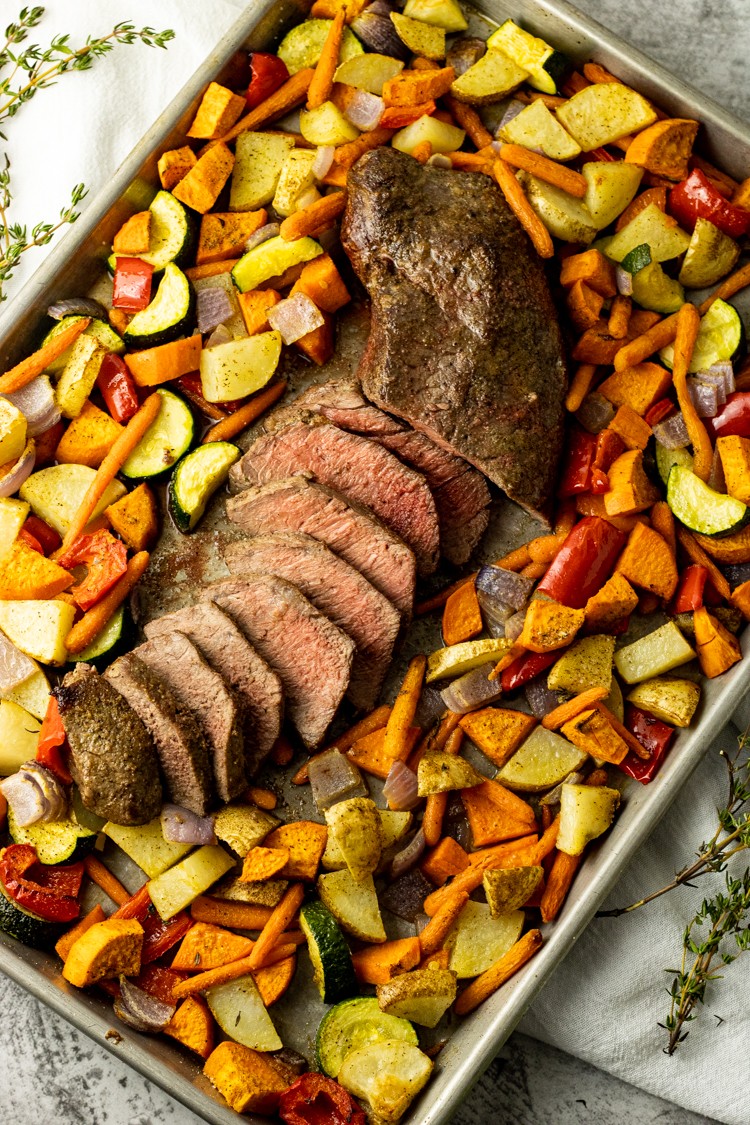 A perfectly roasted beef roast surrounded by colorful roasted vegetables