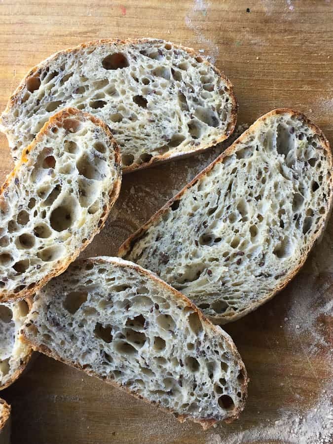 A rustic loaf of sourdough bread made with ancient grains, flax seeds, and chia seeds, showing a close-up of the texture.