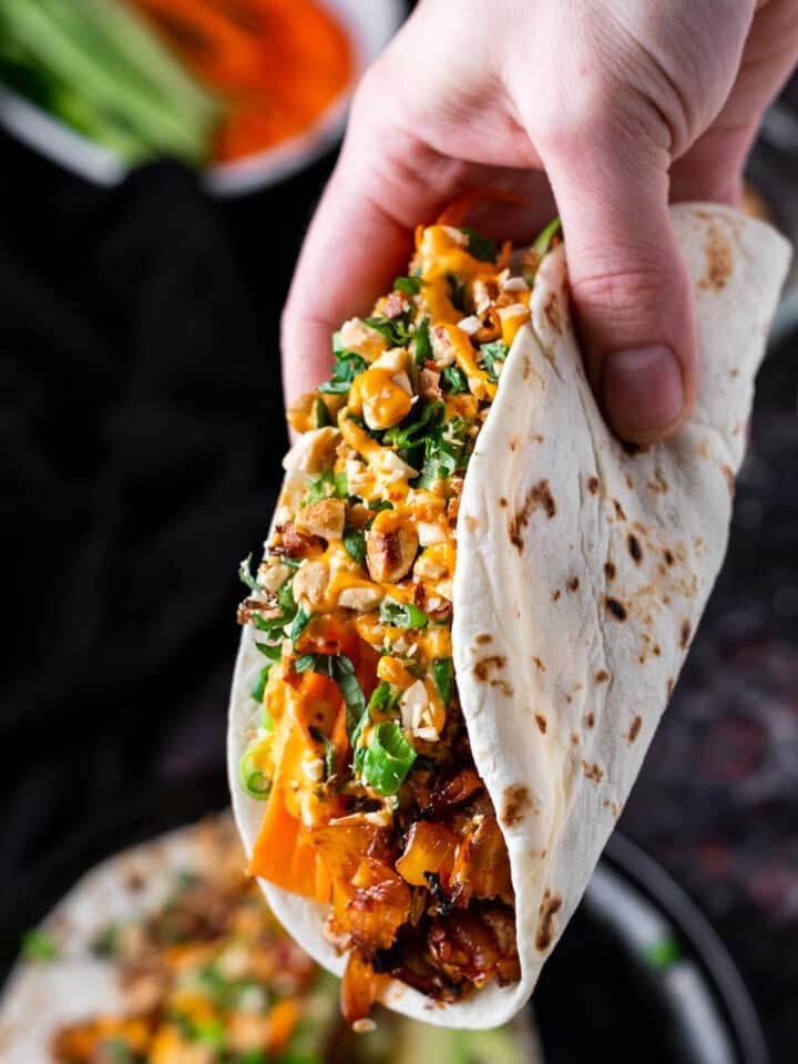 Close-up shot of kimchi and chicken tacos with sesame seeds, garnished with cilantro