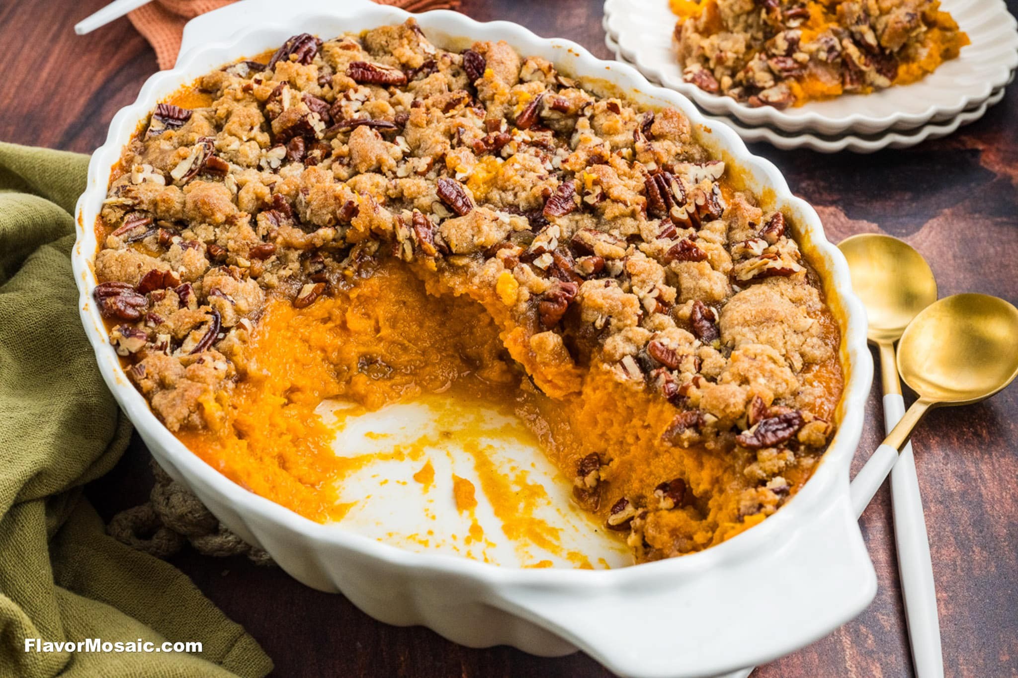 A beautifully golden-brown whipped sweet potato casserole with a glistening pecan streusel topping, garnished with a sprig of rosemary on a rustic wooden table, ready for a holiday meal.