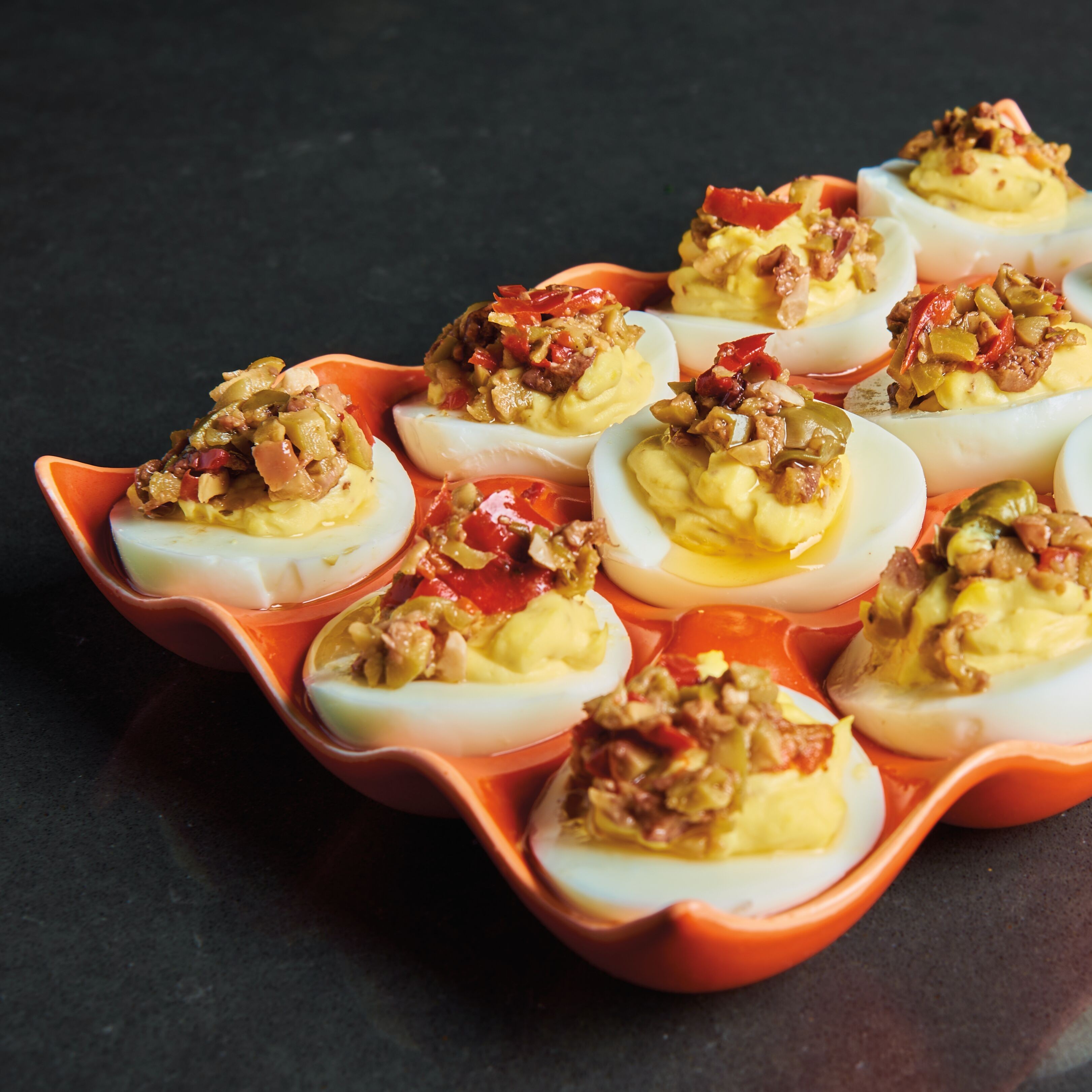 Olive tapenade deviled eggs garnished with fresh herbs