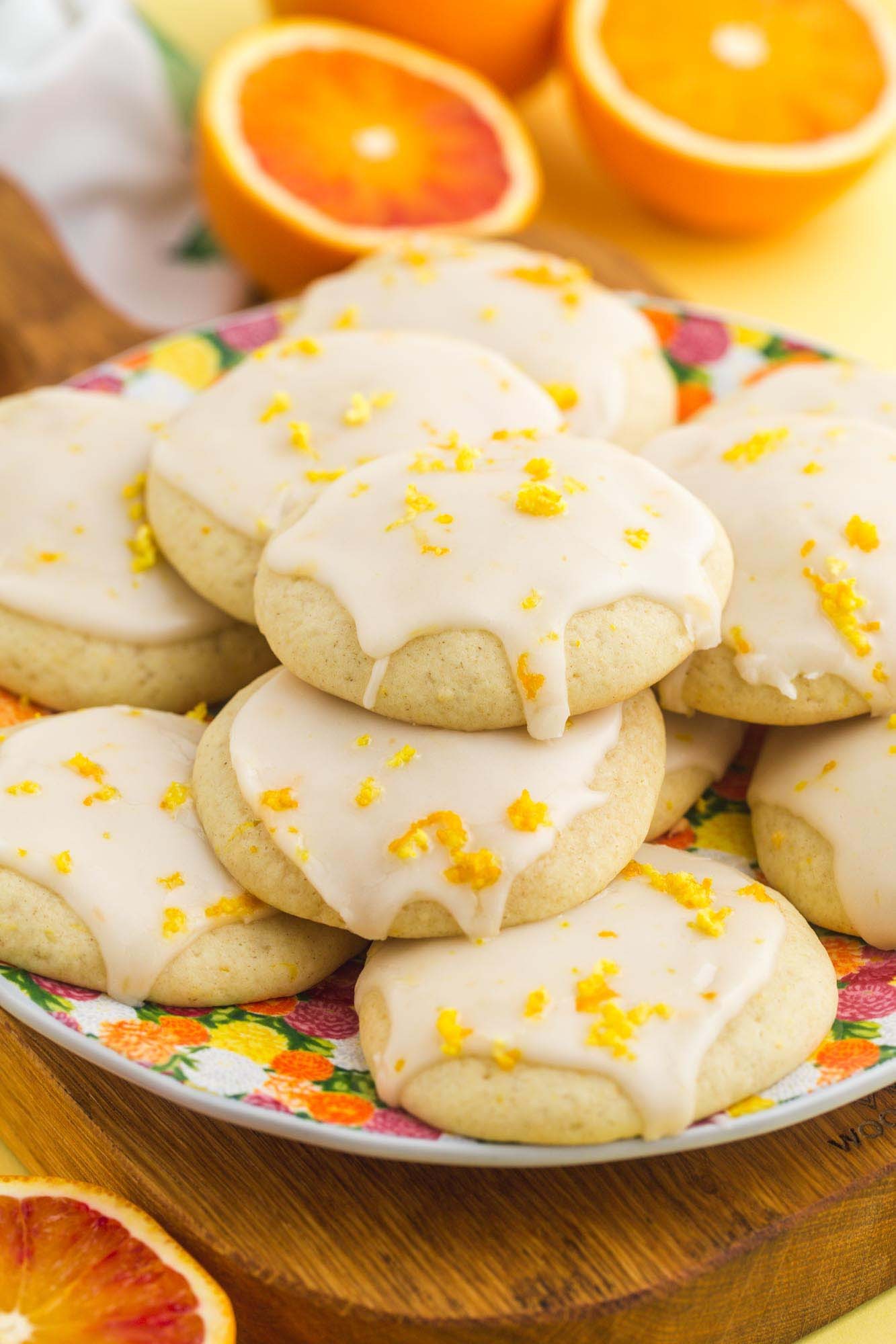 Plate of bright orange zest cookies with fresh orange slices, cozy kitchen background, natural light