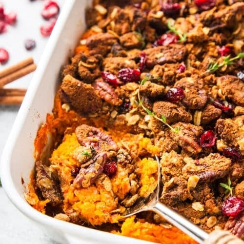 beautifully roasted sweet potato casserole with golden pecan crust, garnished with fresh herbs, rustic holiday setting