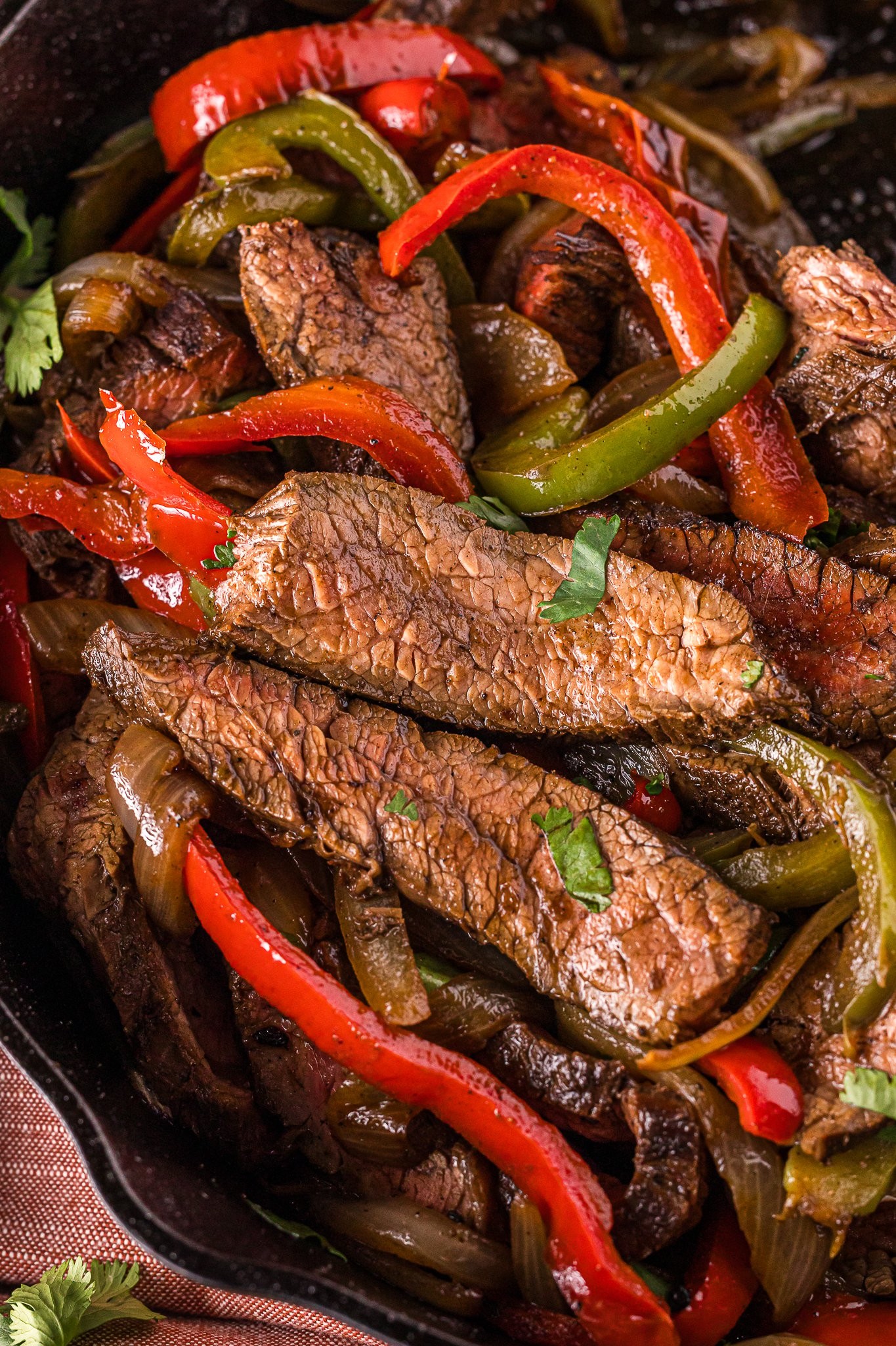Chili-Fired Skillet Beef close-up, sizzling in cast iron pan, garnished with cilantro