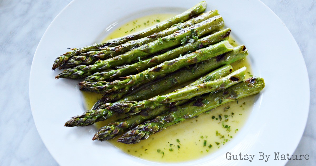 close up of grilled asparagus drizzled with lemon-herb sauce