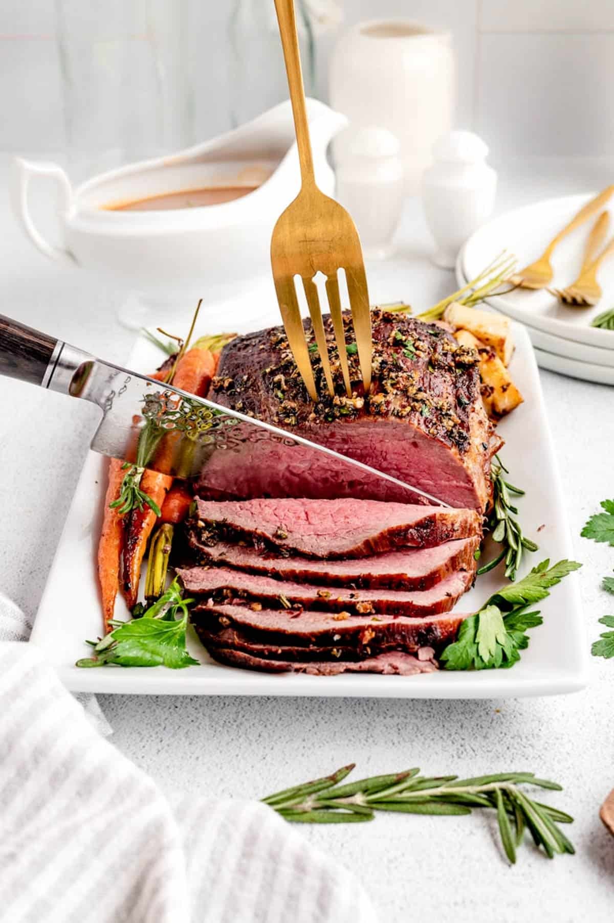 Festive holiday table with a perfectly roasted garlic butter beef roast, garnished with herbs and roasted vegetables