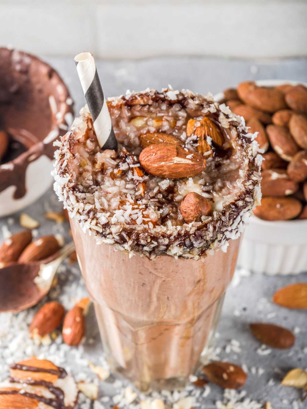 Almond Joy Awakening Smoothie in a glass with coconut flakes and almonds