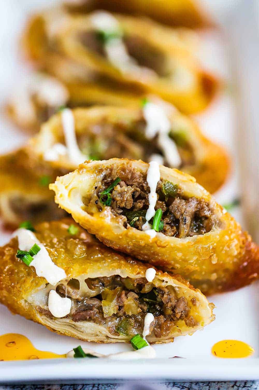 Close-up shot of delicious Philly Cheesesteak Egg Rolls, golden brown and crispy, with melted cheese oozing out.