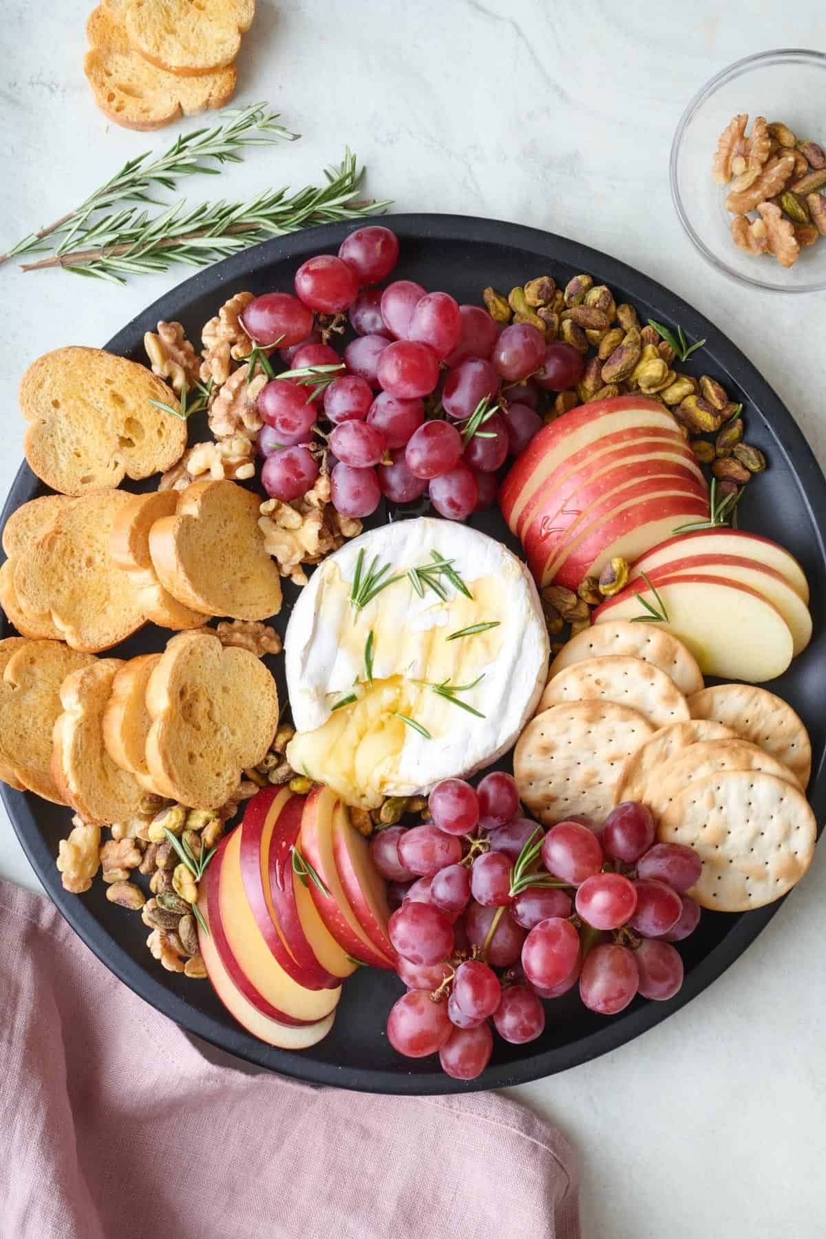 Elegant charcuterie board with a large baked brie in the center, surrounded by fruits, crackers, and cured meats
