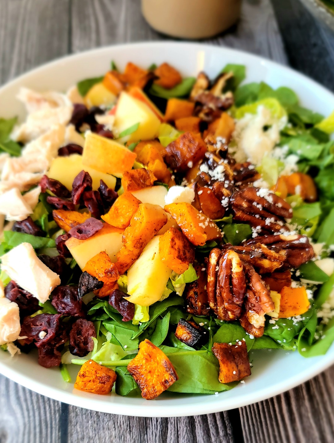 A vibrant and colorful roasted butternut squash salad with pecans and maple-Dijon dressing