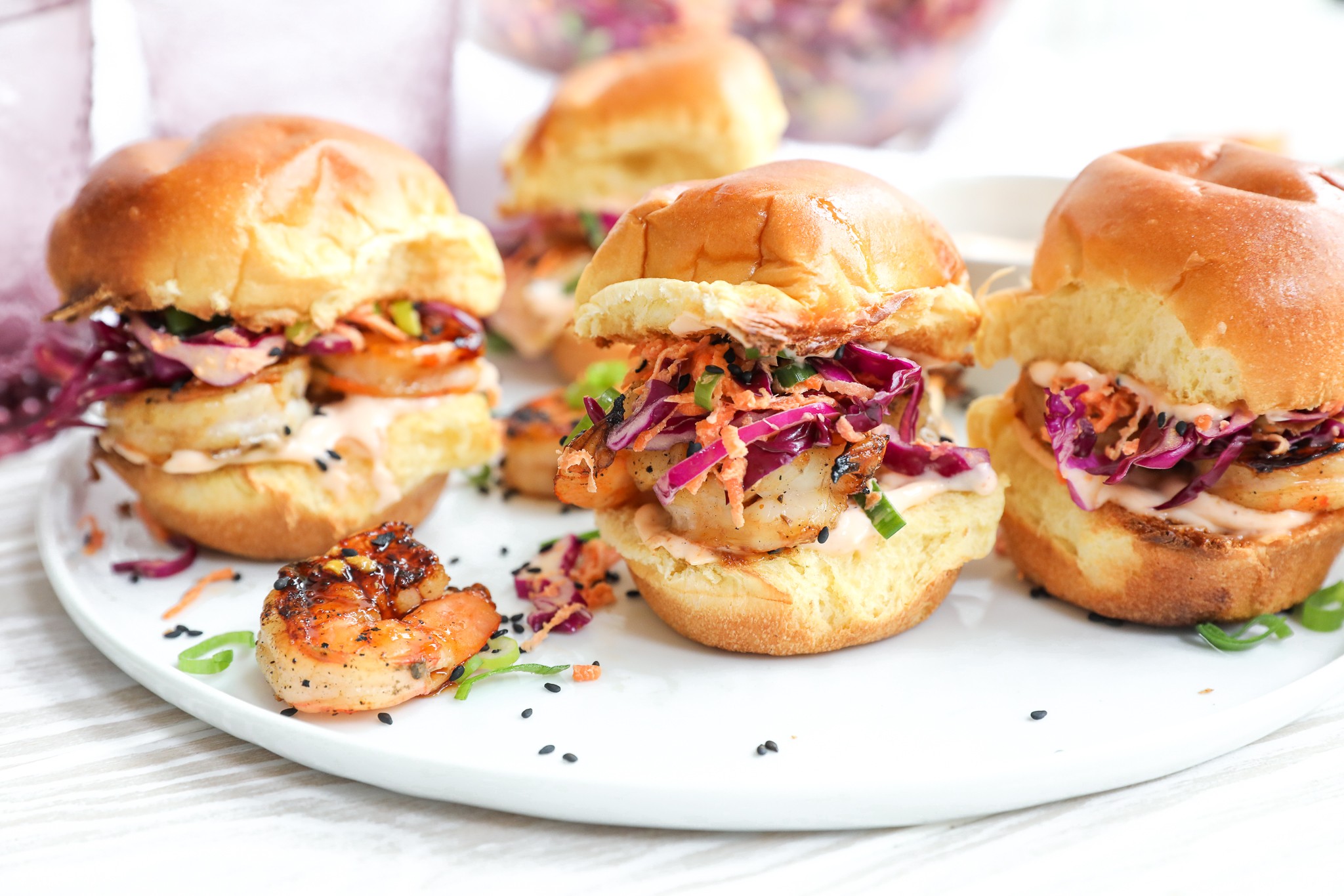 grilled shrimp sliders with fresh toppings on a wooden board