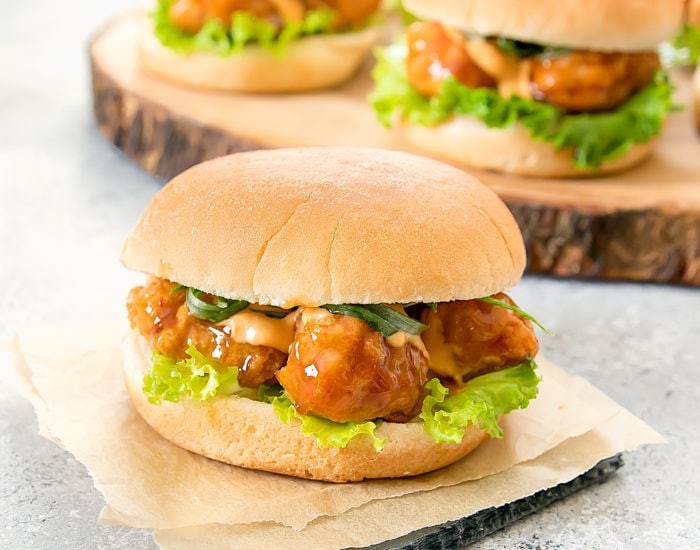 Close-up shot of General Tso's chicken sliders on a rustic wooden board