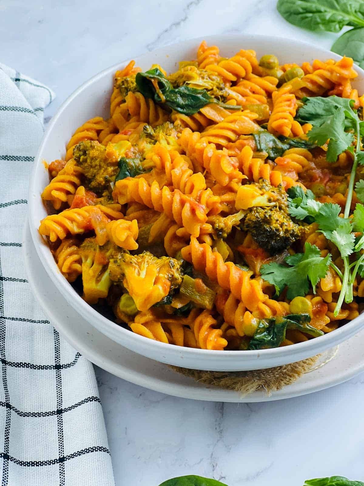 Close-up shot of a vibrant gluten-free pasta dish with lentil and vegetable curry, garnished with fresh cilantro