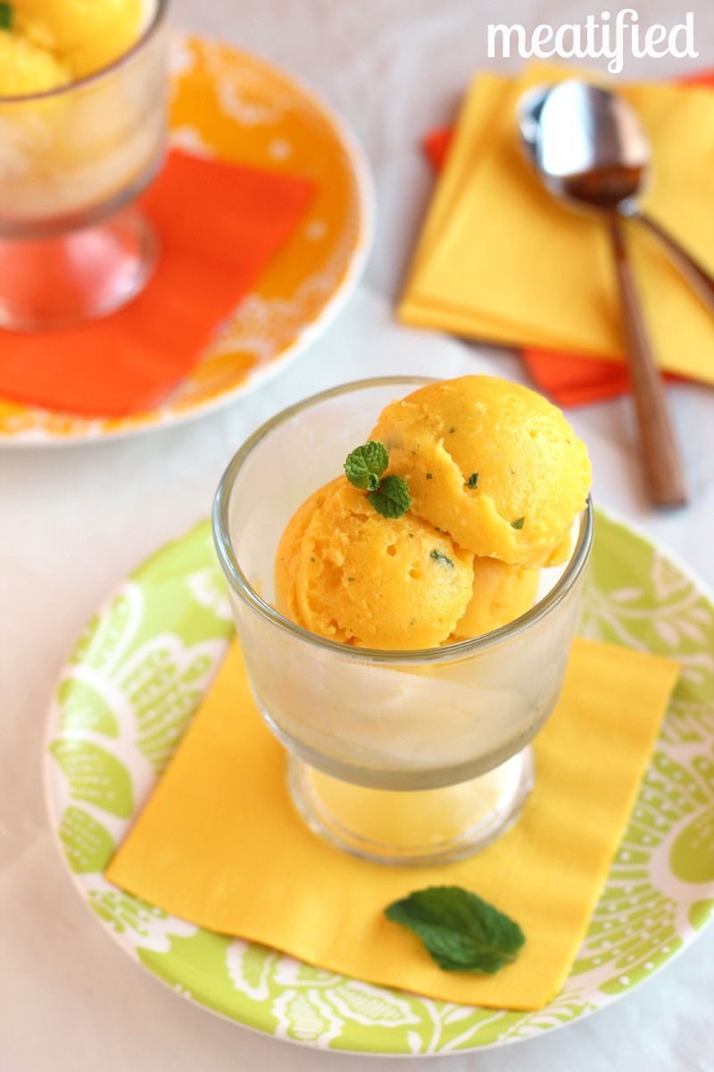 Close-up shot of a vibrant mango sorbet with fresh mint leaves garnish