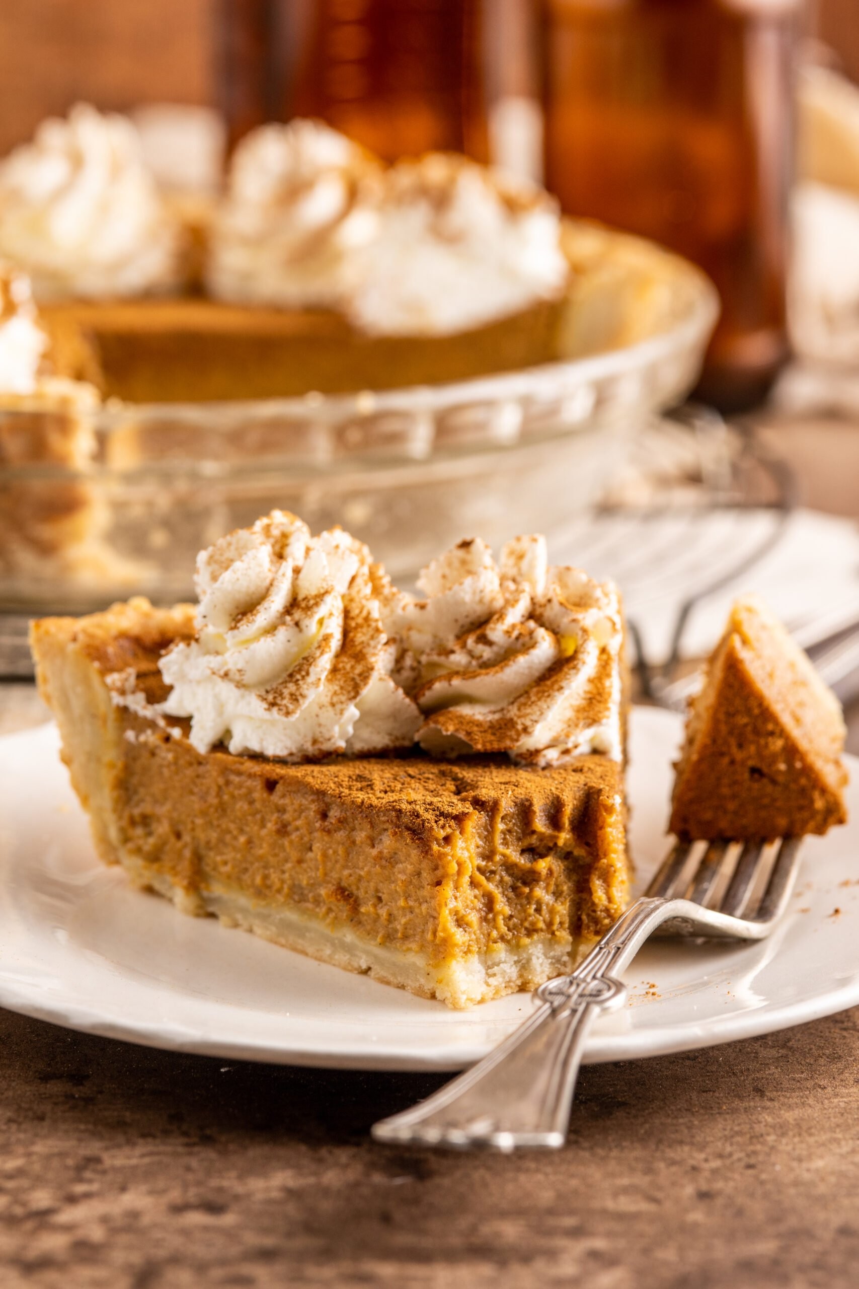 vintage pumpkin pie with custard center on a rustic wooden table, garnished with whipped cream and cinnamon