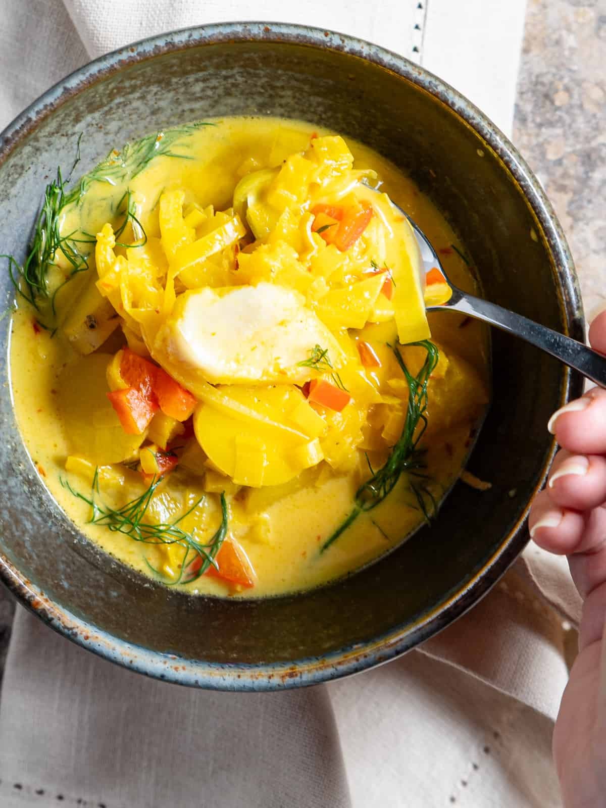 a bowl of fish stew with saffron and potatoes, garnished with fresh herbs