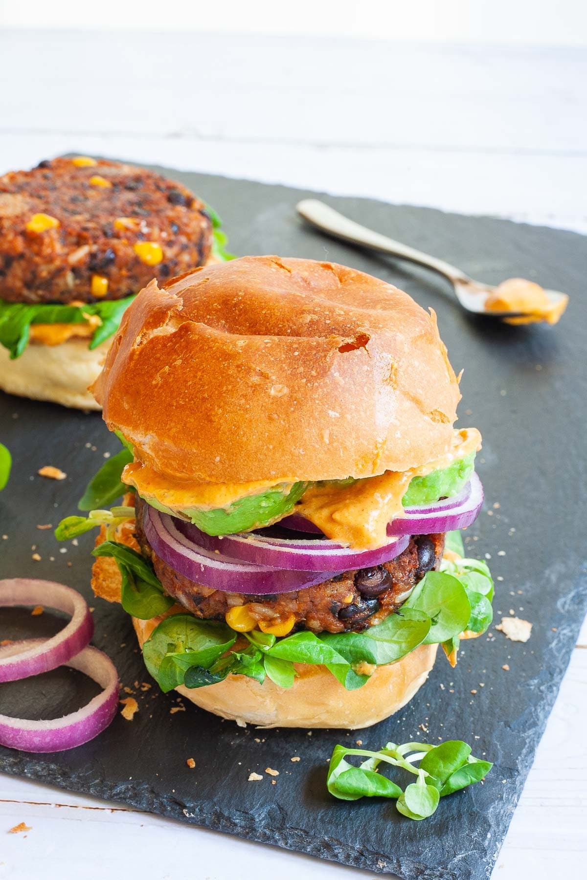 Close-up shot of juicy grilled bell pepper and black bean burgers on toasted buns with lettuce and tomato