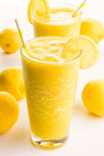 vibrant lemon almond smoothie in a glass with lemon slices and almonds