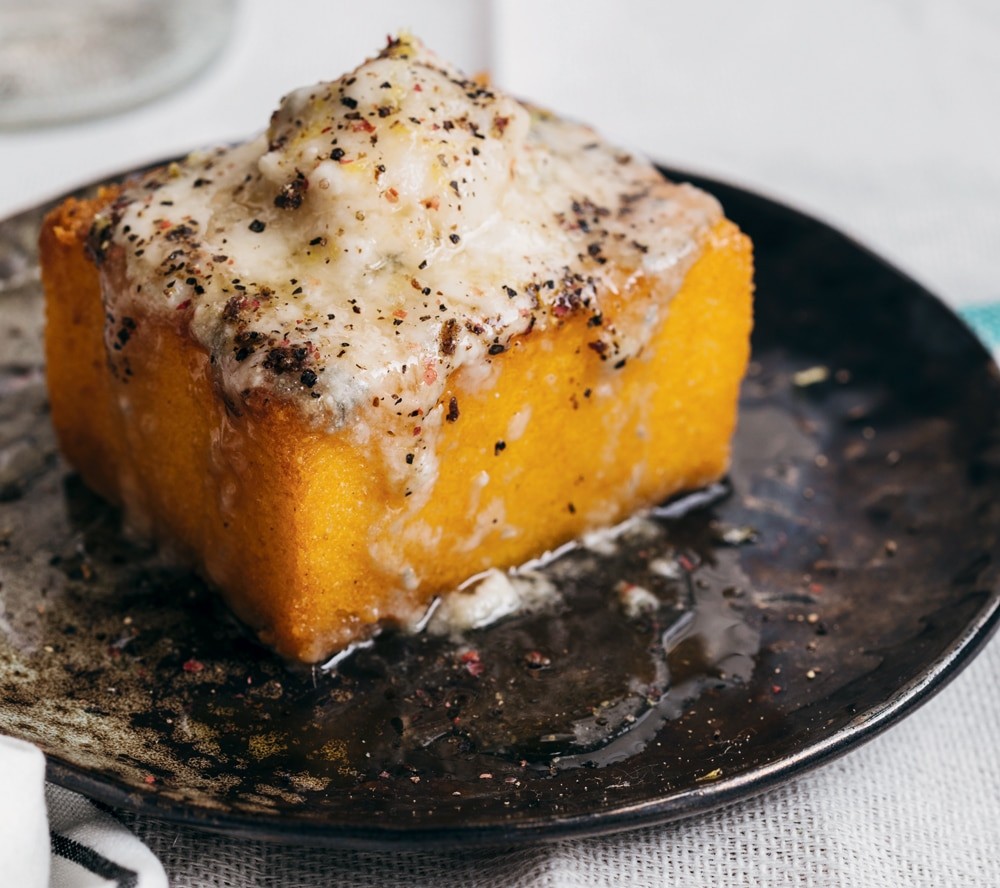 Close-up shot of golden brown polenta and gorgonzola cakes with walnuts, drizzled with honey